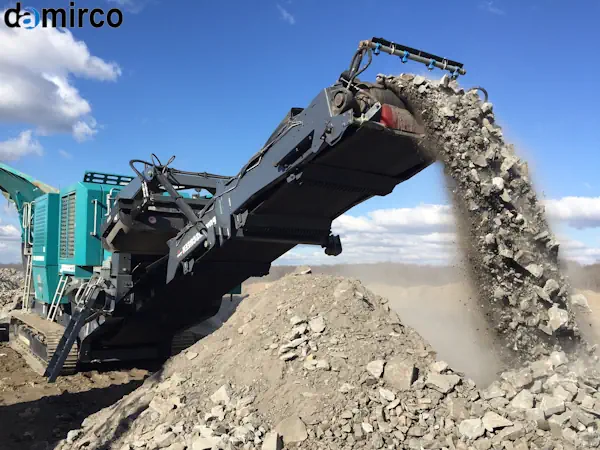 دستگاه سنگ شکن فکی در حال خرد کردن بتن و آجرهای حاصل از تخریب یک ساختمان برای بازیافت