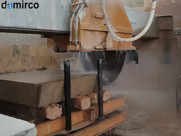 یک دستگاه برش سنگ نمای صنعتی در حال برش دقیق یک اسلب بزرگ سنگ تراورتن در کارخانه سنگبری