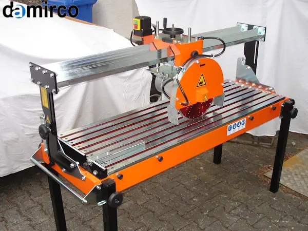 مجموعه‌ای از قطعات یدکی دستگاه برش سنگ شامل دیسک برش، بلبرینگ و قطعات الکتریکی روی یک میز کار