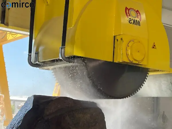 یک دستگاه برش سنگ رومیزی در حال برش دقیق یک قطعه سنگ گرانیت در یک کارگاه صنعتی