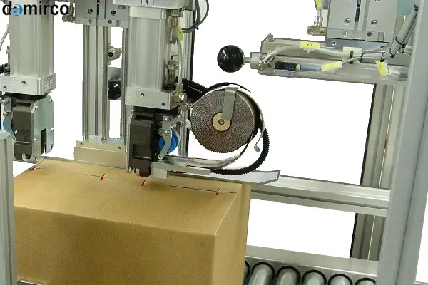 تکنسین در حال انجام تعمیر و نگهداری روی یک دستگاه منگنه کوب کارتن صنعتی در کارخانه