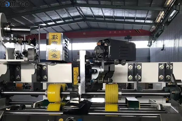 کارگر در حال استفاده از دستگاه منگنه کوب کارتن بادی برای بسته بندی جعبه های مقوایی در یک انبار صنعتی