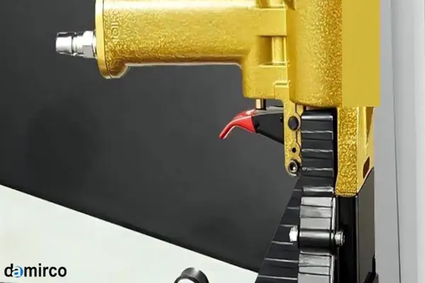 نمای نزدیک از یک دستگاه منگنه کوب کارتن بادی در حال بستن درب یک جعبه مقوایی قهوه‌ای رنگ